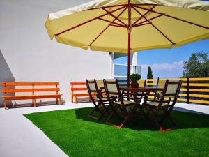 a table with chairs and a large yellow umbrella at Nikoli Apartments in Benitses