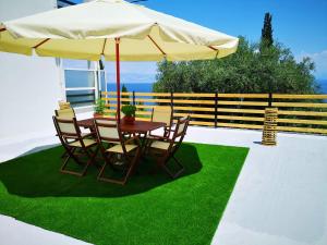 a table and chairs with an umbrella on a lawn at Nikoli Apartments in Benitses