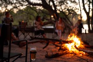a group of people sitting around a fire at Ichingo Chobe River Lodge by Mantis in Punga