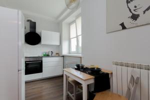 uma cozinha com armários brancos e uma pequena mesa em ShortStayPoland Staszica (B76) em Varsóvia