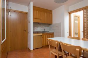 cocina con mesa, sillas y barra en Appartamenti Corte Residence en Borca di Cadore