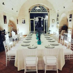 un comedor grande con una mesa larga con sillas blancas en B&B Masseria Conti Filo, en Altamura
