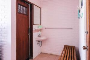 a bathroom with a sink and a toilet and a wooden door at RedDoorz Syariah near Kopeng Treetop Adventure in Salatiga