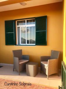 a patio with two chairs and a window at Cantinho Solpraia in Porto Santo