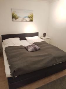 a bed with a gray blanket and a pillow on it at 2 Zimmer Ferienwohnung Ostseetraum Haffkrug in Scharbeutz