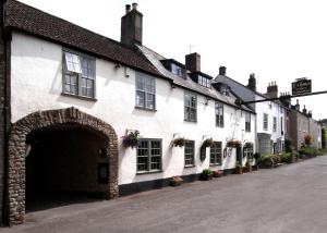 a row of white buildings with flowers on the windows at The George at Nunney in Frome