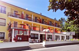 ein gelbes Gebäude mit Tischen und Sonnenschirmen davor in der Unterkunft Hotel Auszeit in Sankt Kanzian am Klopeiner See