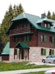 a large wooden house with a green roof at Apartments Durmitor in Žabljak