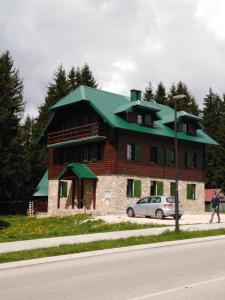 uma casa grande com um telhado verde numa rua em Apartments Durmitor em Žabljak