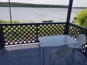 Una mesa y sillas en un balcón con vista al agua. en Portul Dunarii, en Hîrşova
