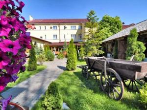 a wooden cart sitting in the grass next to a building at Stanislavskiy Dvir in Ivano-Frankivsʼk