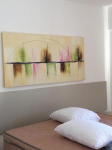 uma pintura na parede acima de uma cama com uma almofada em Evian thermas Residence em Caldas Novas