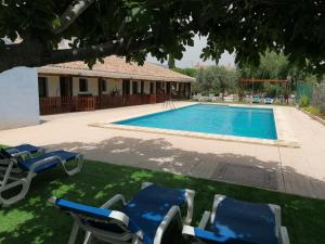 a swimming pool with chairs and a house at Casas Rurales Noguericas in Archivel