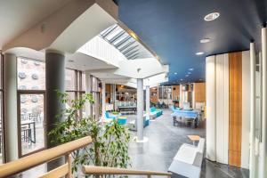 Blick auf die Lobby einer Bibliothek mit blauen Stühlen und Tischen in der Unterkunft Auberge de Jeunesse de Mons in Mons