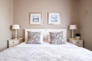 a bedroom with a white bed with two lamps at Na Genoeg Holiday Home in Paternoster