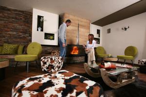 a man and woman standing in a living room with a fireplace at Hotel Vedig in Santa Caterina Valfurva