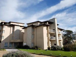 a large apartment building with a lawn in front of it at Departamentos Sea Point By D&G in Carilo