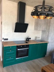 cocina con armarios verdes, fregadero y TV en Butas centre, en Klaipėda