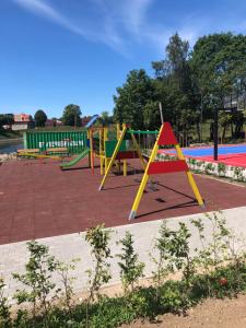 un parque con parque infantil con columpios amarillos y rojos en Butas centre, en Klaipėda