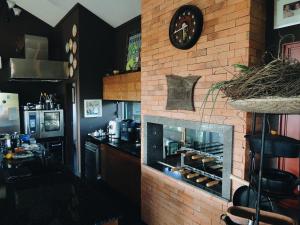 a kitchen with a brick wall with a fireplace at Casa Marrom do Chef in Araranguá