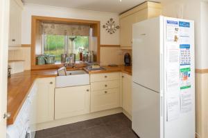 a kitchen with a white refrigerator and a sink at Fasgadh Crofters Cottage in Broadford