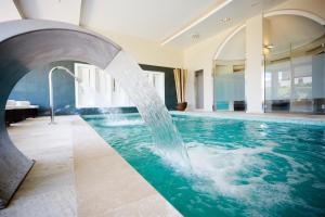 a pool with a water fountain in a building at Grupotel Macarella Suites & Spa in Son Xoriguer