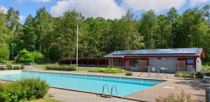 a house with a swimming pool and a building with solar panels at Stuga på Hallandsåsen in Hjärnarp