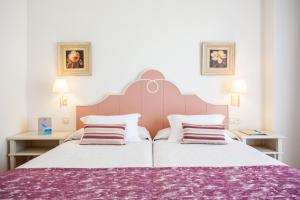 a bedroom with a large bed with a purple blanket at Grupotel Macarella Suites & Spa in Son Xoriguer