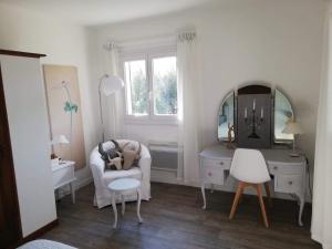 Dieses weiße Zimmer verfügt über einen Stuhl, einen Schreibtisch und einen Spiegel. in der Unterkunft Chambre lumineuse, calme absolu in Allauch