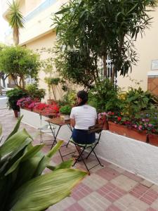 a woman sitting on a bench in front of a garden at Hotel Avenida 31 in Marbella