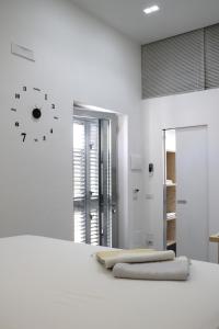 a white bedroom with a clock on the wall at LOFT 52 in Margherita di Savoia