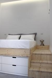 a bedroom with a wooden bed with white sheets at LOFT 52 in Margherita di Savoia