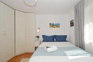 um quarto branco com uma cama com almofadas azuis em Bora bora Apartment em Kaštela