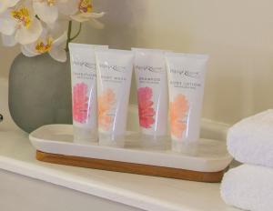 a group of four moisturizers on a shelf with flowers at Sandals Grande Antigua - All Inclusive Resort and Spa - Couples Only in Saint Johnʼs