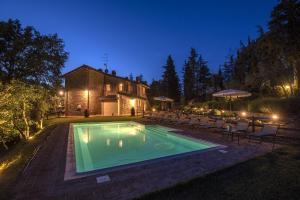 een zwembad voor een huis 's nachts bij B&B Country House Poggio Del Drago in Ponticino
