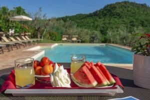 un vassoio di frutta e succhi su un tavolo accanto alla piscina di B&B Country House Poggio Del Drago a Ponticino