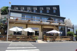 un bâtiment avec des tables et des parasols devant lui dans l'établissement Hotel du Lac - Au Bord du Lac, à La Tour-dʼAuvergne