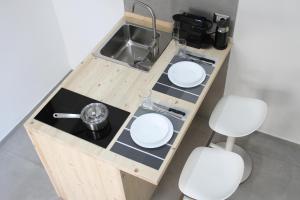 a small kitchen with a sink and two white stools at LOFT 52 in Margherita di Savoia