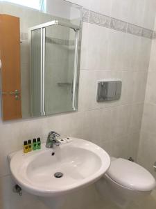 a bathroom with a sink and a toilet and a mirror at Sun N Blue Hotel in Sarandë