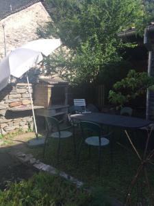 einen Tisch, Stühle und einen Regenschirm im Hof in der Unterkunft Rustico Cadrobi 20 in San Vittore