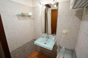 uma casa de banho em azulejos brancos com um lavatório e um espelho. em Casa rural con mucho encanto en un entorno mágico em Horta de San Joan