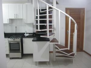 uma cozinha com armários brancos e uma escada em espiral em Lindo apartamento dúplex em Salvador