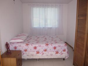 a bed in a bedroom with a window and a table at Lindo apartamento dúplex in Salvador