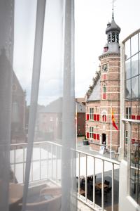 einen Blick vom Balkon eines Gebäudes mit einem Uhrturm in der Unterkunft Hotel De Kroon Gennep in Gennep
