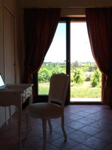 um quarto com uma cadeira, uma mesa e uma janela em Contado San Lorenzo B&B and Wine em Castilenti