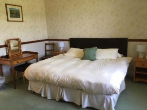 een slaapkamer met een groot wit bed met 2 kussens bij Craignuisq Farmhouse in Pitlochry