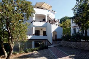 a white building with a balcony and trees at Apartments Matic in Njivice