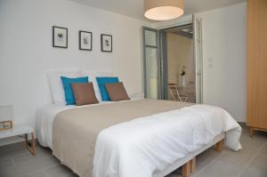 a white bedroom with a large bed with blue pillows at Le Clos des Salins in Toulouse