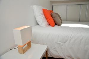 a white bed with pillows and a television on a table at Le Clos des Salins in Toulouse