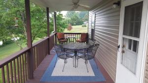 een patio met een tafel en stoelen op een veranda bij Cabin by the lake in Burnside